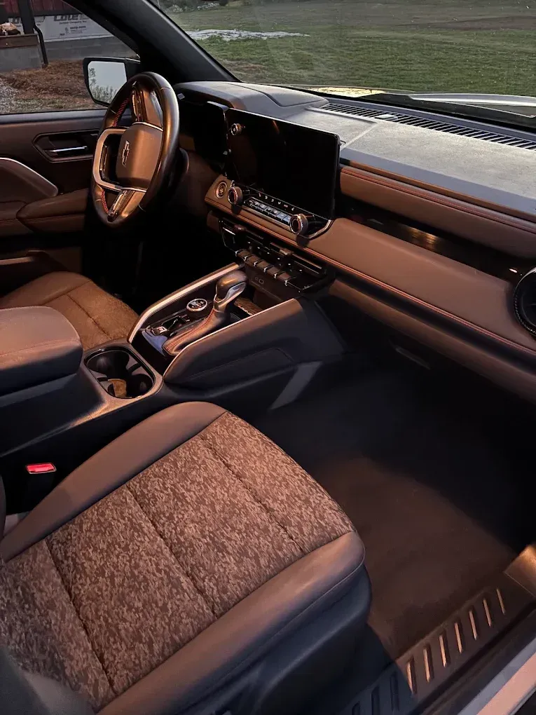 Luxury car interior with tan and black seats, center console, and dashboard at dusk.