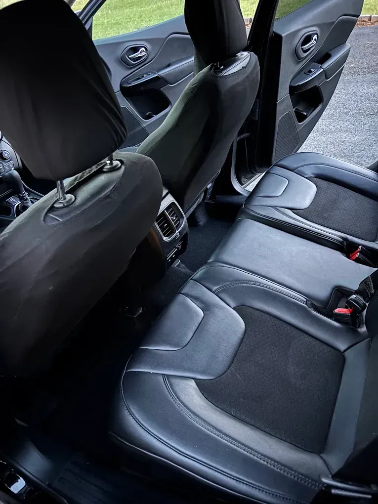 Car interior with black rear seats, door panels, and seatbelts visible.
