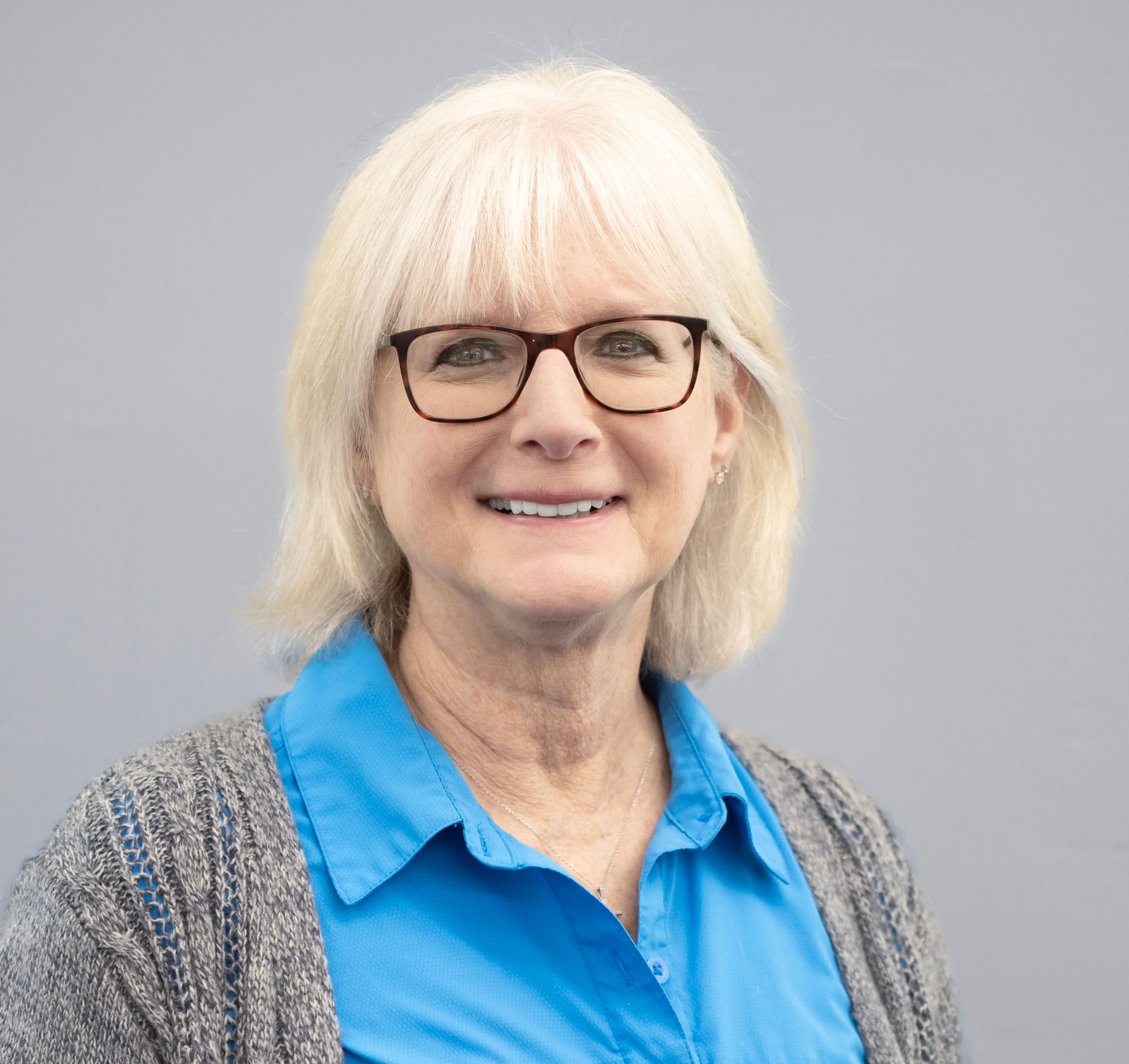 A woman is sitting at a desk with a laptop and a vase of flowers.