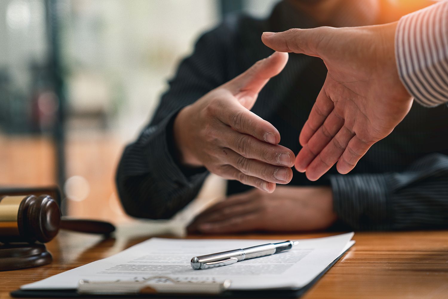 View of a lawyer and their client, about to shake hands on top of some documents. View of a lawyer and their client, about to shake hands on top of some documents.