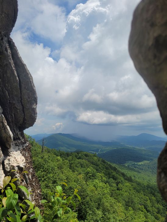 Rocky cliff framing a lush green valley under cloudy skies