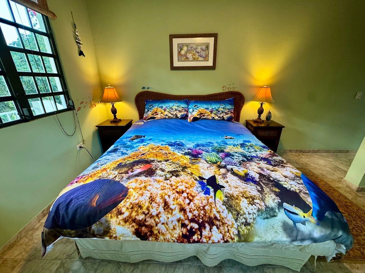 Bedroom with coral reef-themed bedding, nightstands, lamps, and a window.