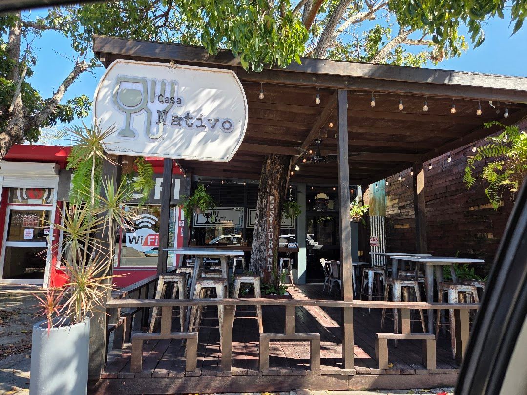 Casa Nativo plate: fried plantains, seasoned rice, beans, pork, and salsa bowl on a wooden table.