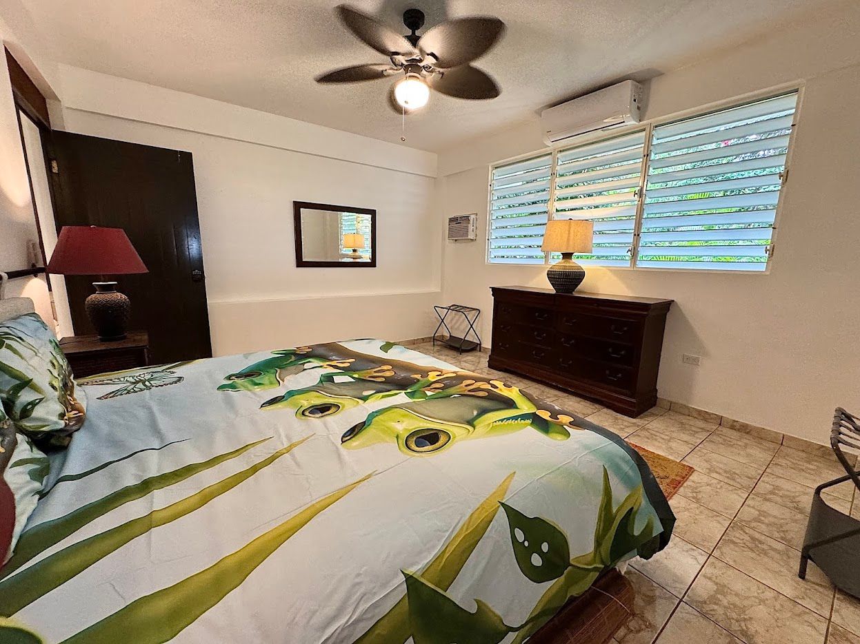 Bedroom with turtle-themed bedspread, dark furniture, ceiling fan, and window blinds.