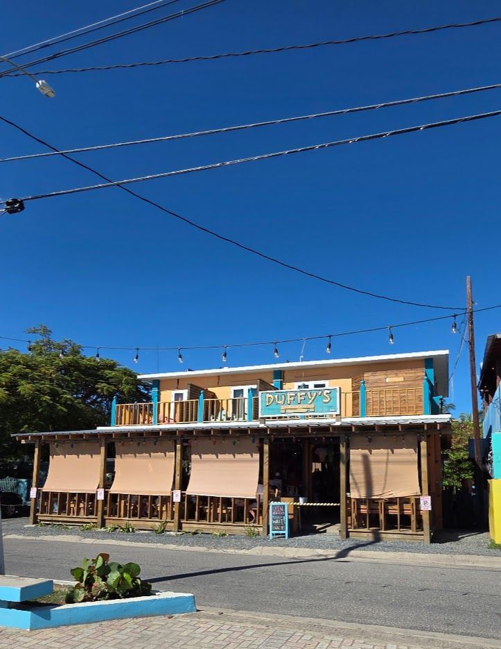 Sidewalk cafe by the beach; people dining under umbrellas and awnings.