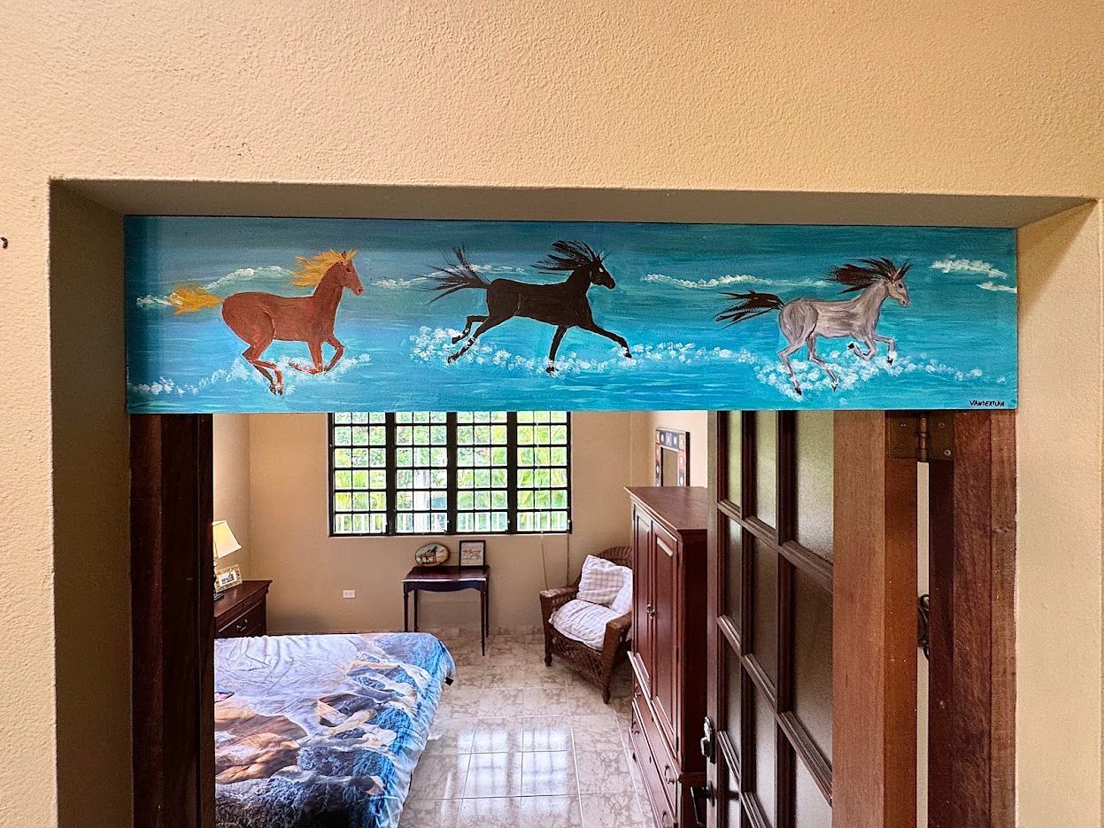 Horses painted on blue above an interior doorway, bedroom visible below.