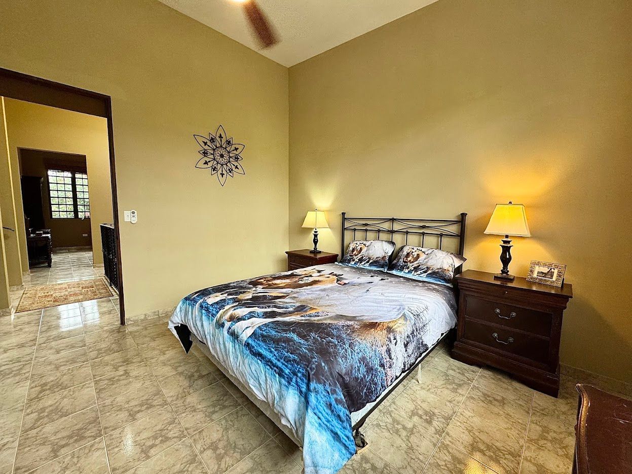 Bedroom with a bed, nightstands, lamps, and a doorway to another room. Yellow walls.