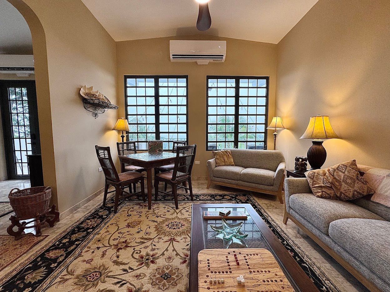 Living room with table, couches, lamps, and windows.