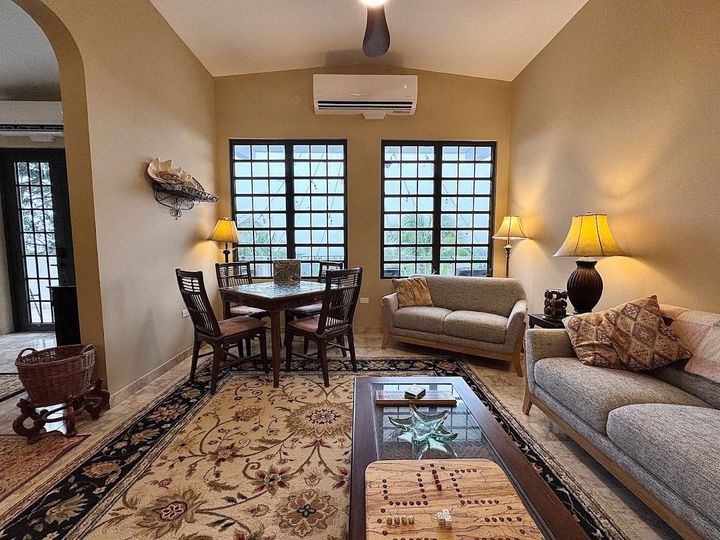 Living room with table, couches, lamps, and windows.