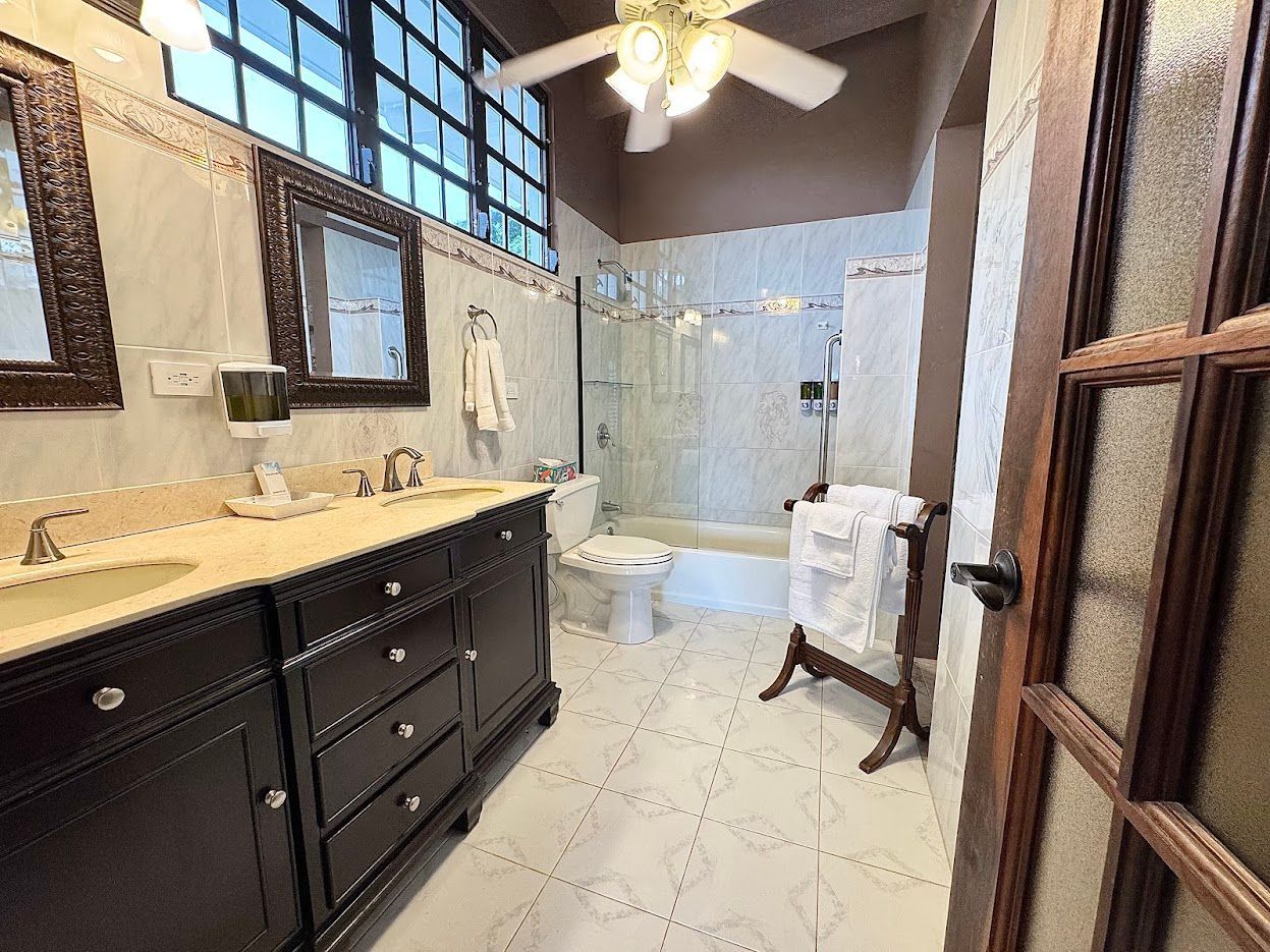 Bathroom with dark vanity, white tile floor, and a shower.