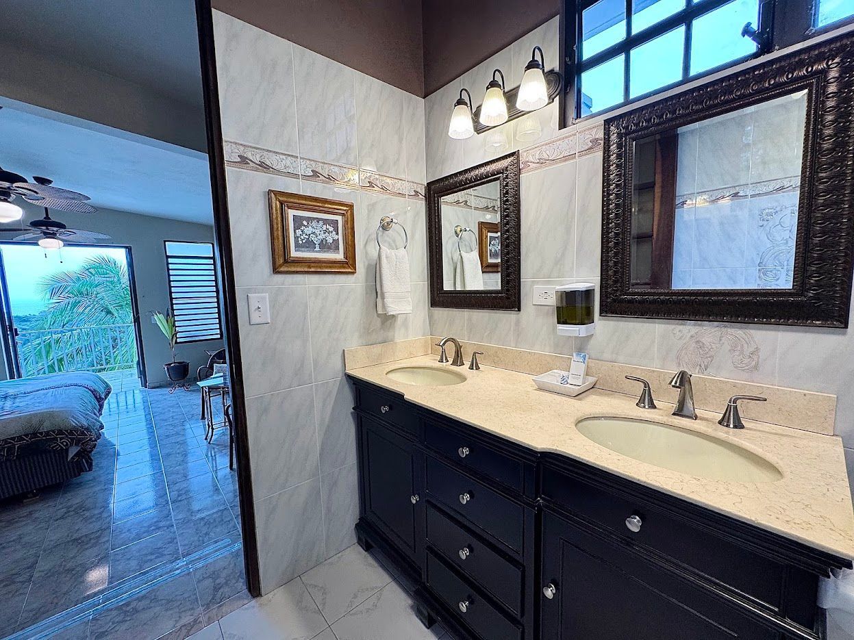 Bathroom with dark cabinets, light countertops, two sinks, and decorative mirrors.