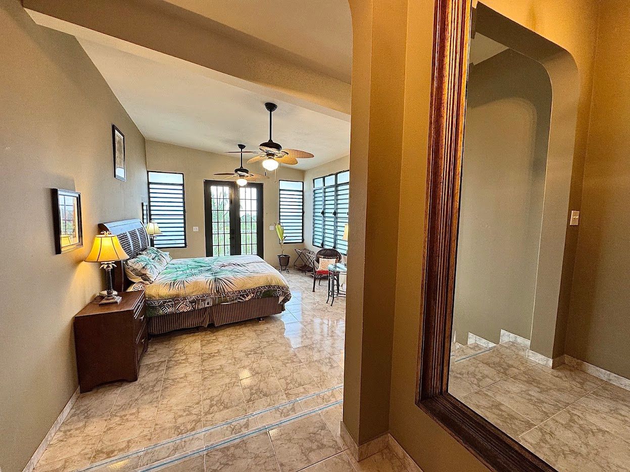 Bedroom with bed, nightstand, ceiling fan, and large mirror.