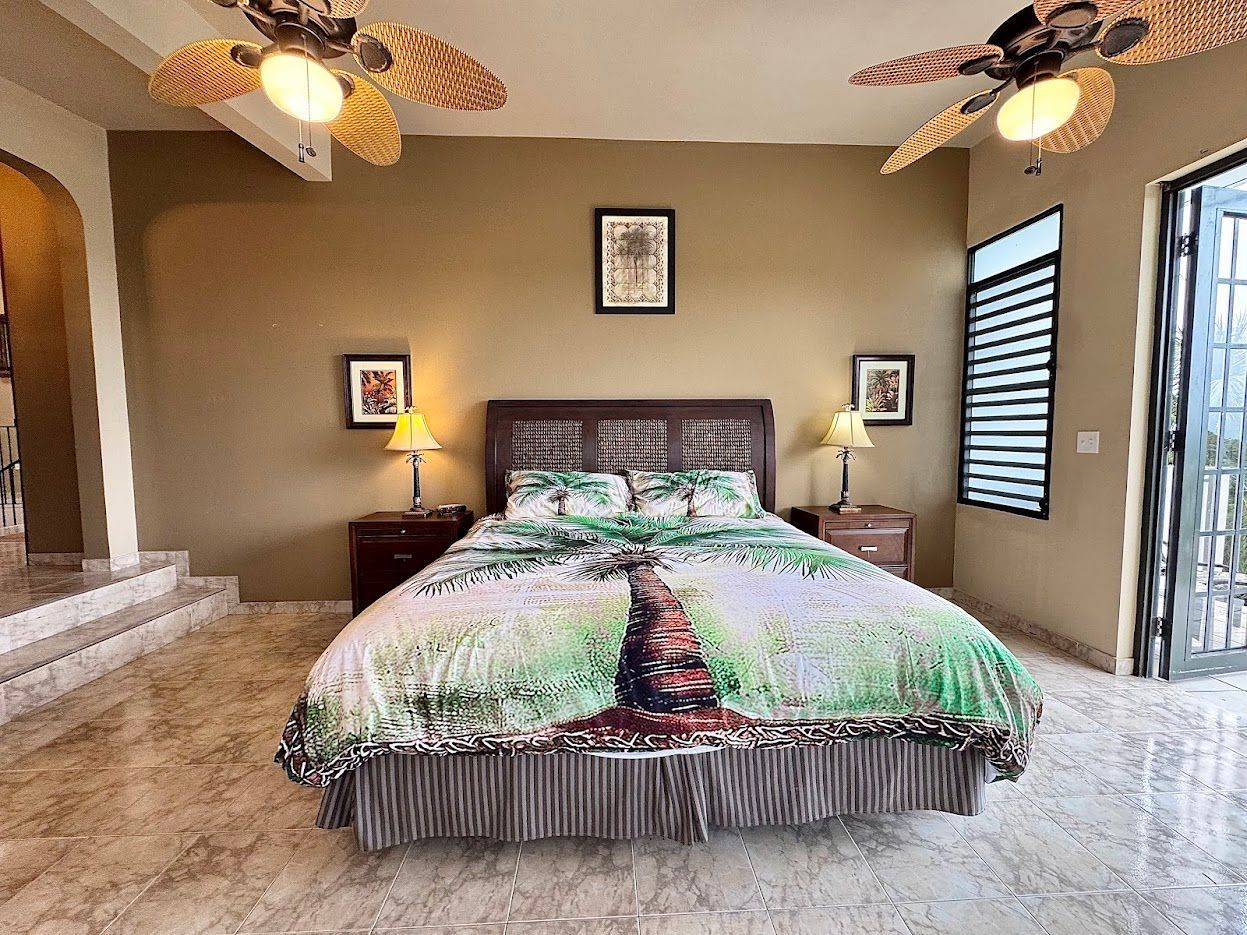 Bedroom with double bed, two nightstands, two ceiling fans, and a window.