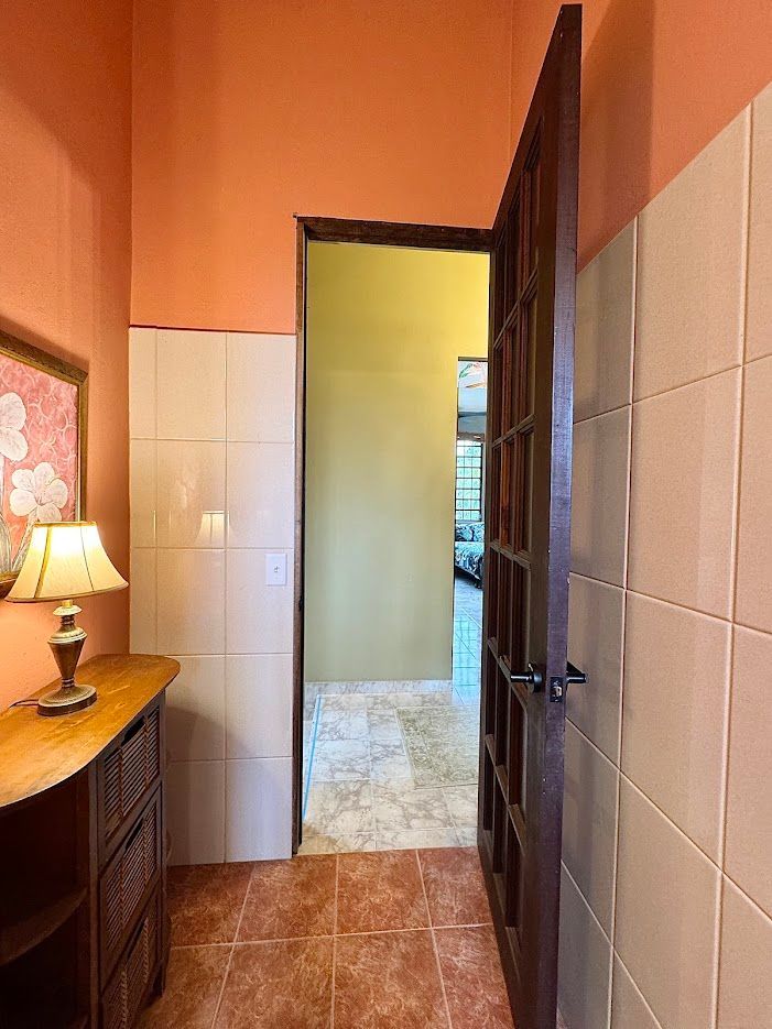 Hallway with orange and white walls, brown door open to another room.