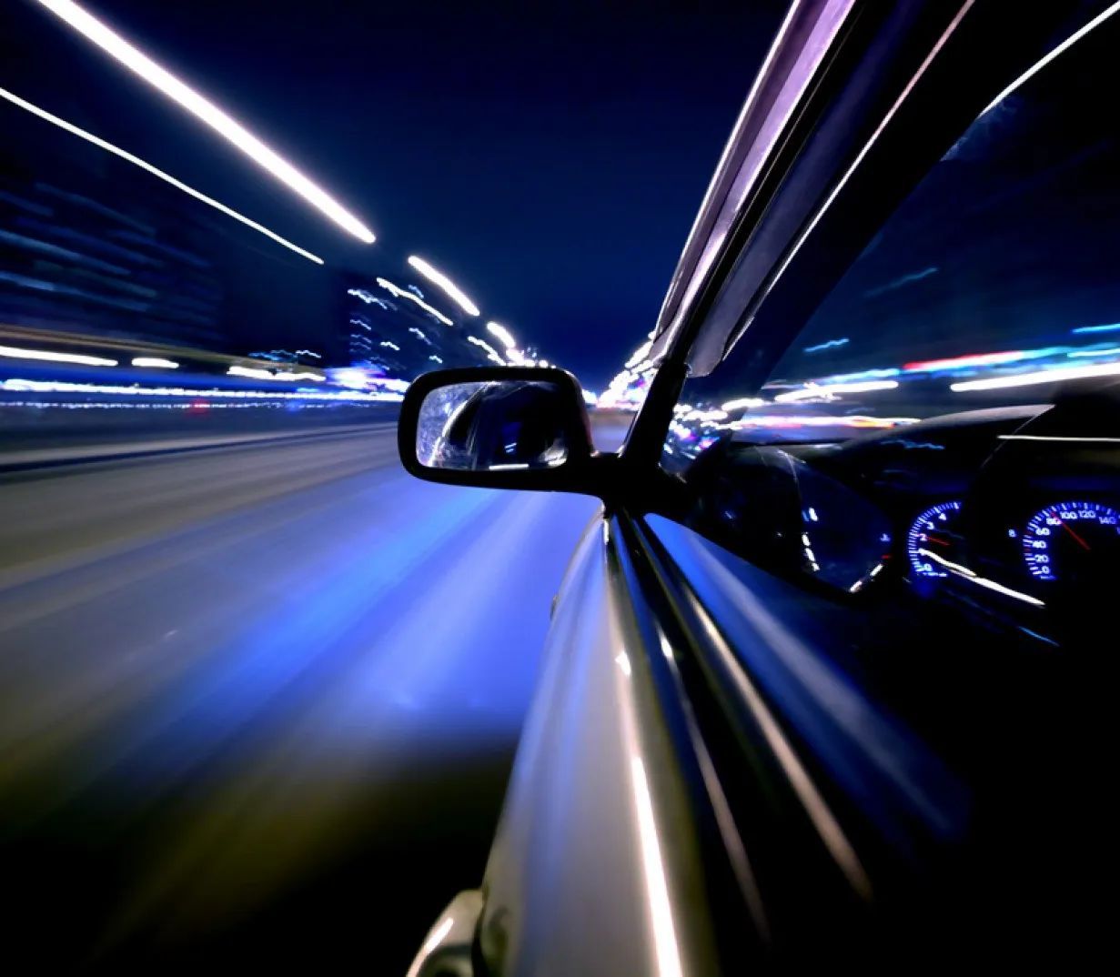 Car driving fast at night with blurred streaks of light.