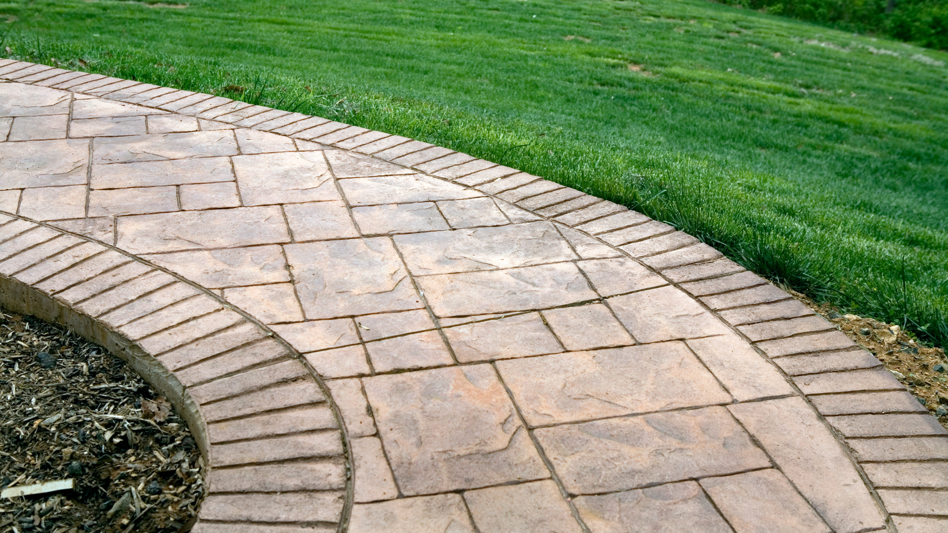 A brick walkway going through a lush green field