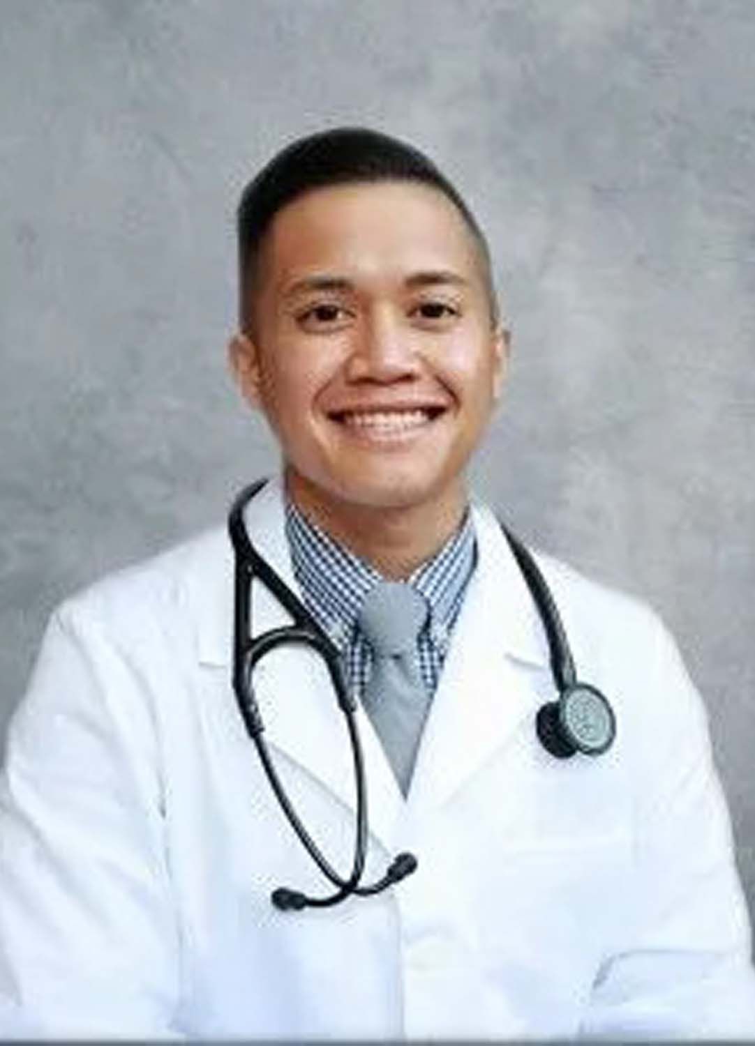 Doctor in a white coat with a stethoscope smiling at the camera.