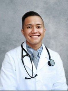 Doctor in a white coat with a stethoscope smiling at the camera.
