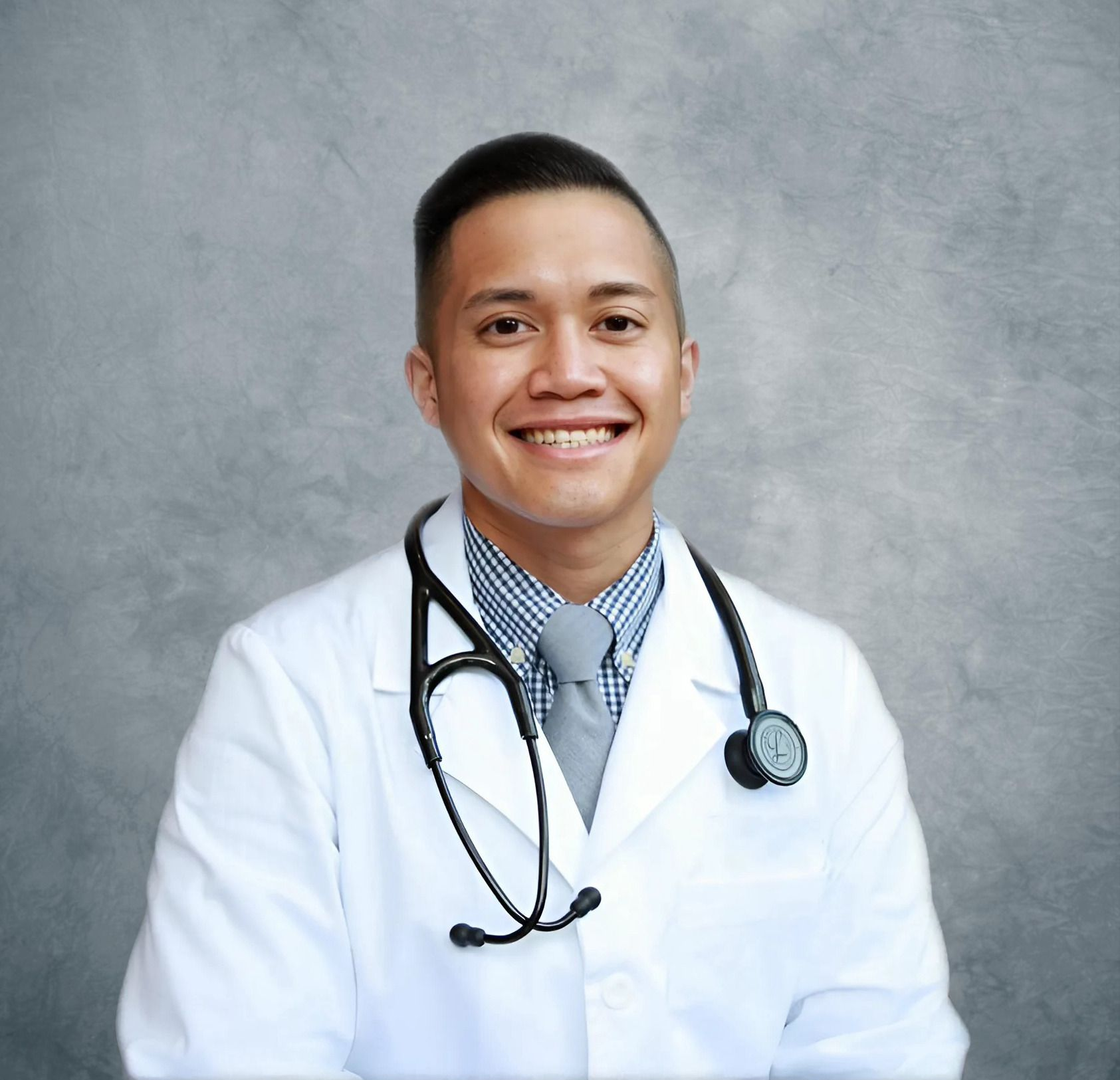 Doctor in a white coat with a stethoscope smiling at the camera.