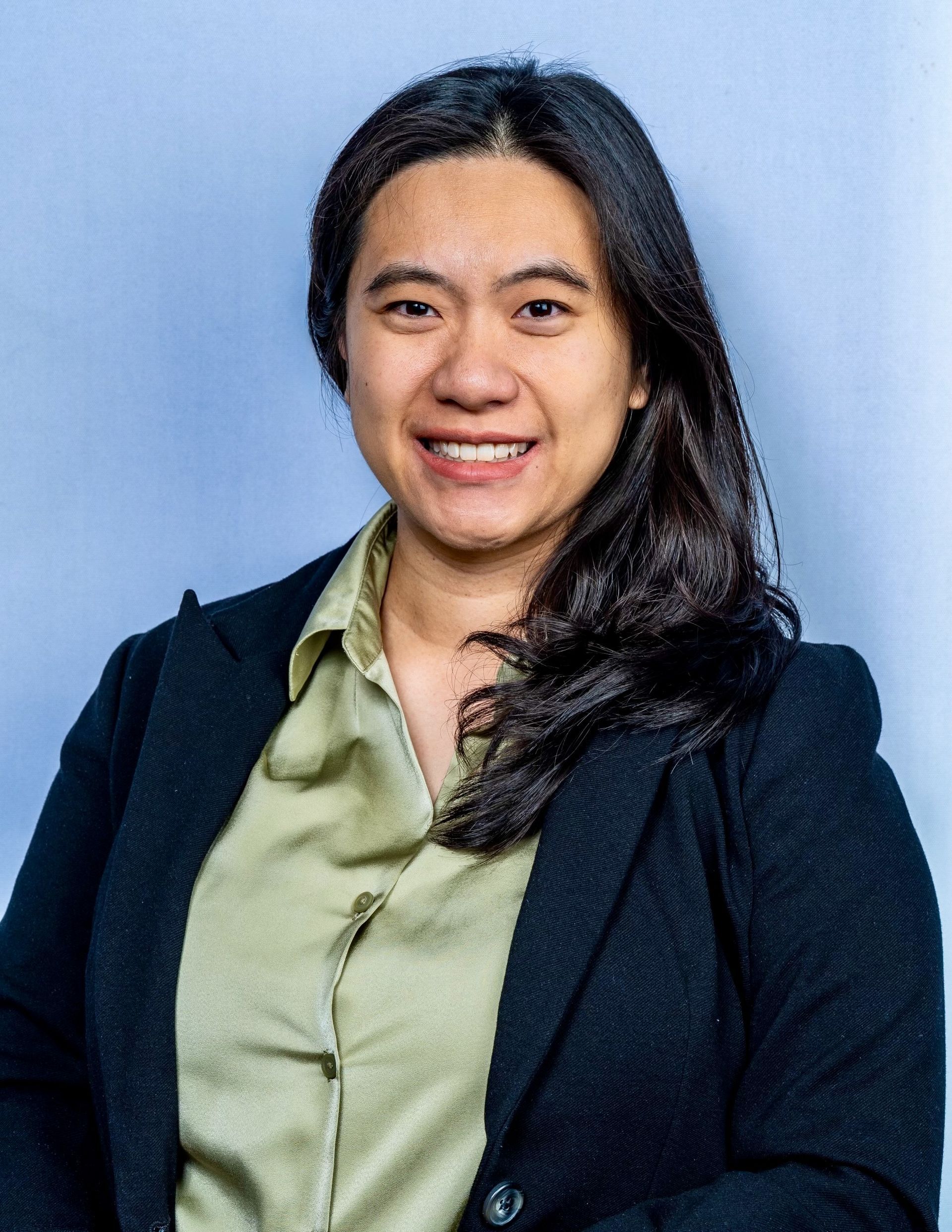 Woman in a white lab coat smiling, with