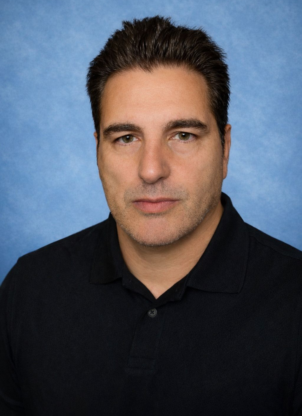 Man in white coat, looking at the viewer. Blue and white background.