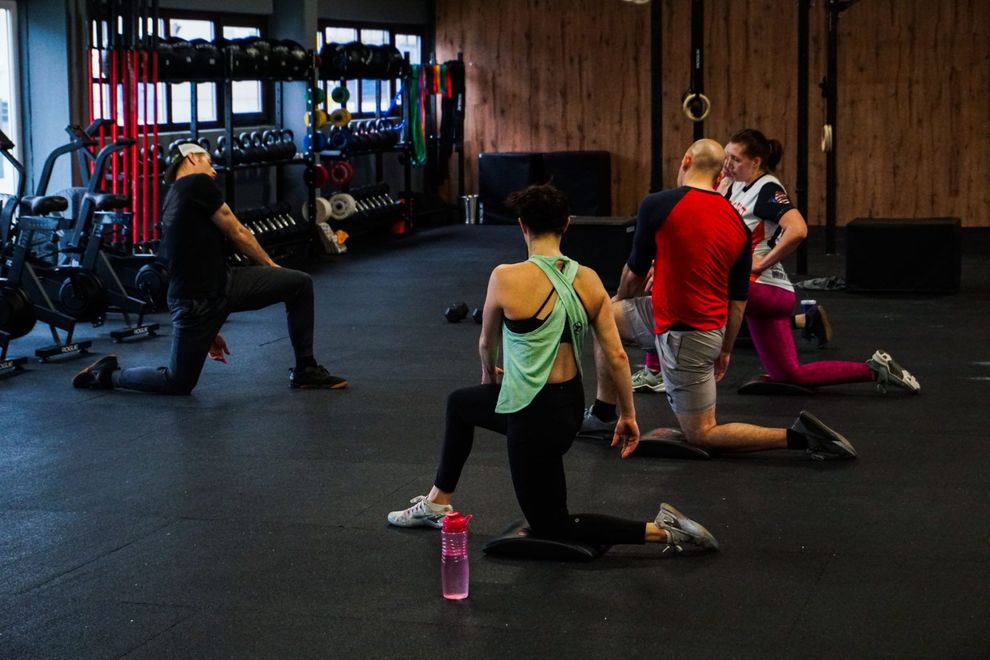 Eine Gruppe von Menschen macht in einem Fitnessstudio Dehnübungen.
