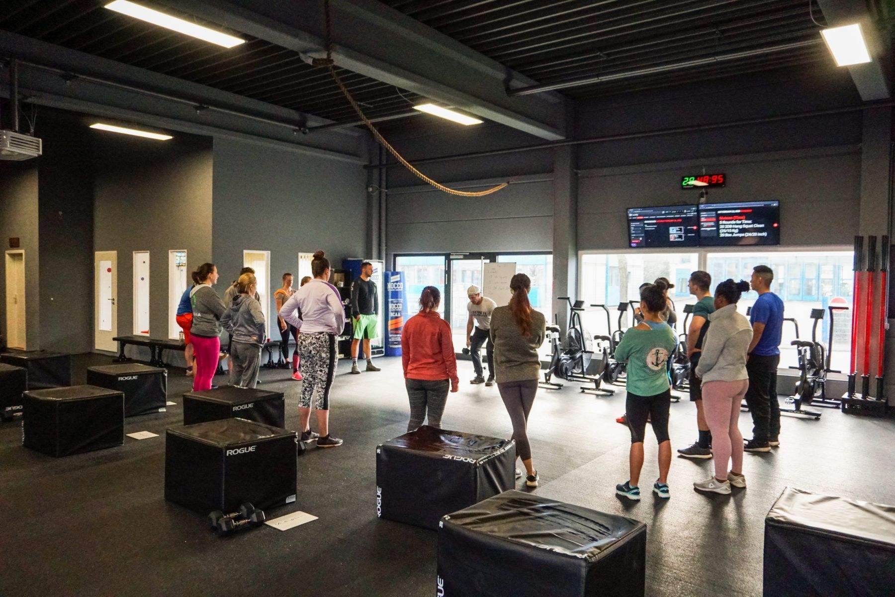 Eine Gruppe von Leuten steht in einer Turnhalle und unterhält sich.
