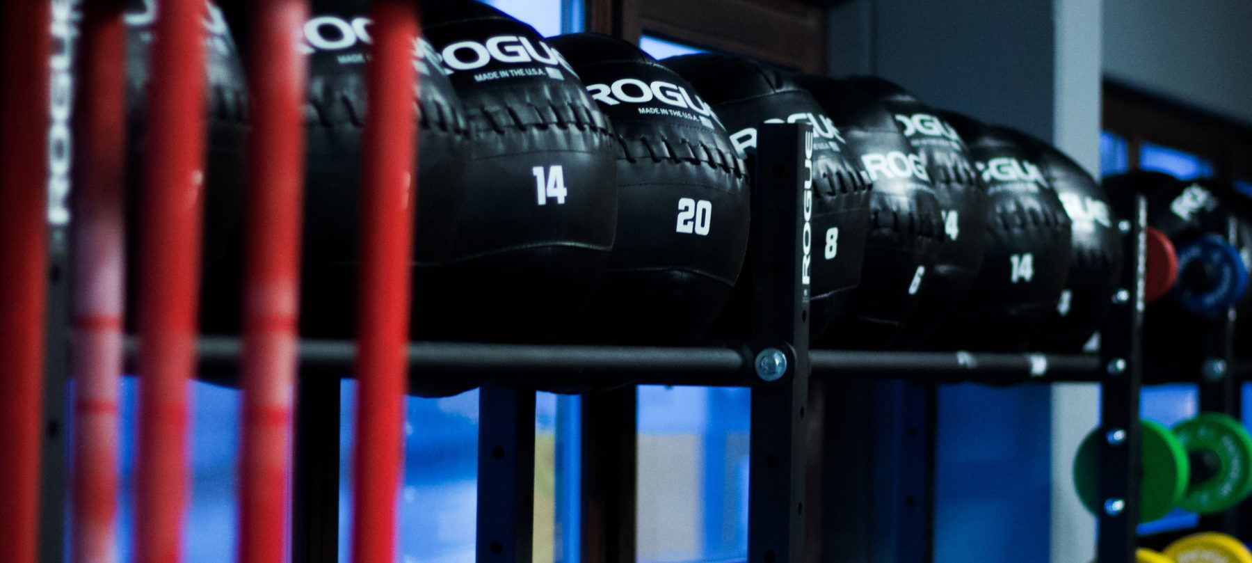 In einem Fitnessstudio sind mehrere Gymnastikbälle auf einem Ständer aufgereiht.