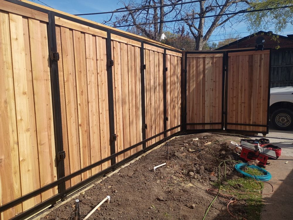 Wooden privacy fence panels installed along a curved backyard boundary with dirt and garden tools nearby