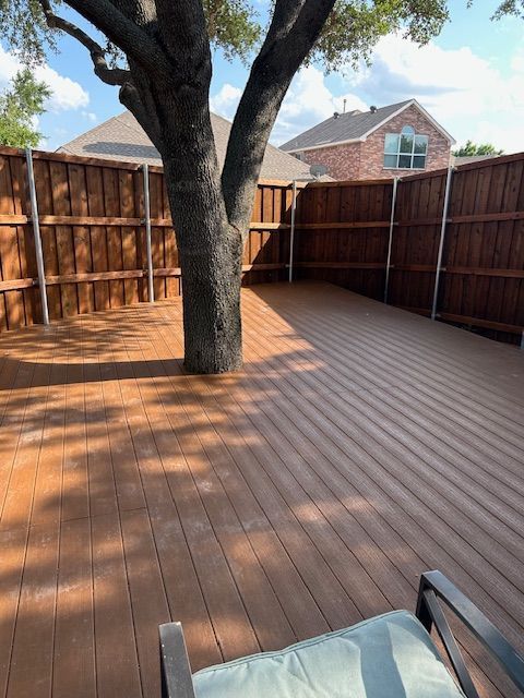Backyard wooden deck with a large tree growing through the center and fenced sides