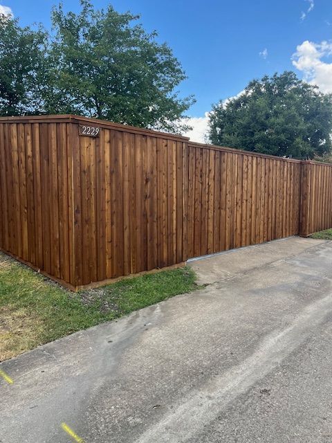 Wooden privacy fence along a driveway under a blue sky