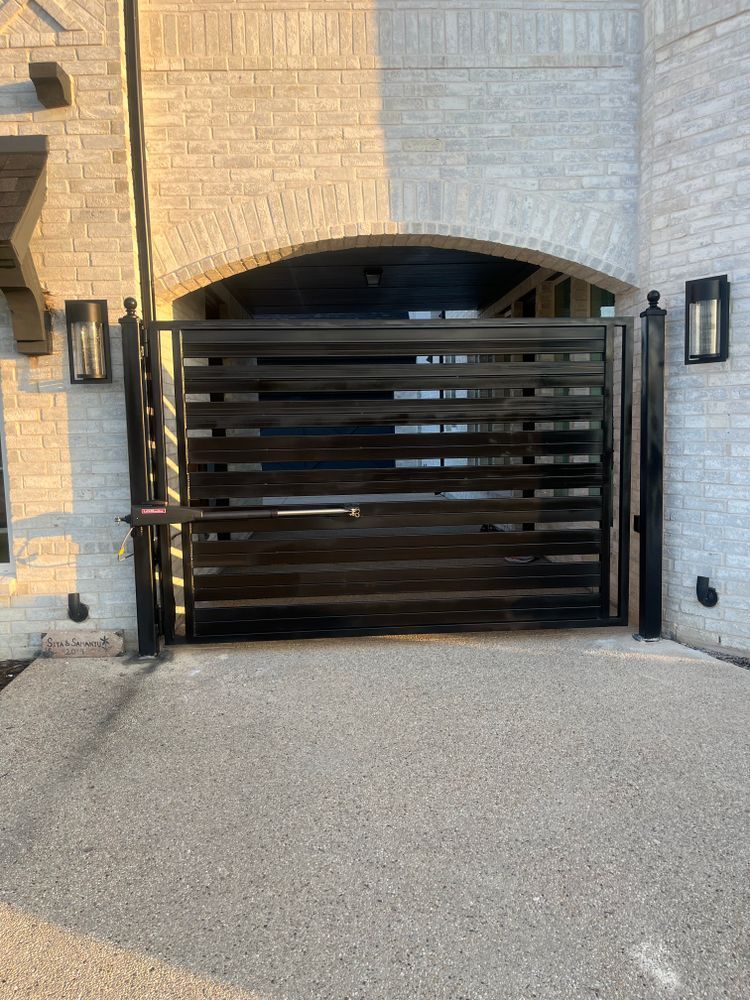 Dark wood driveway gate beneath a stone archway on a residential driveway