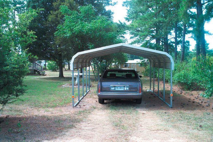 A car is parked under a carport in a yard