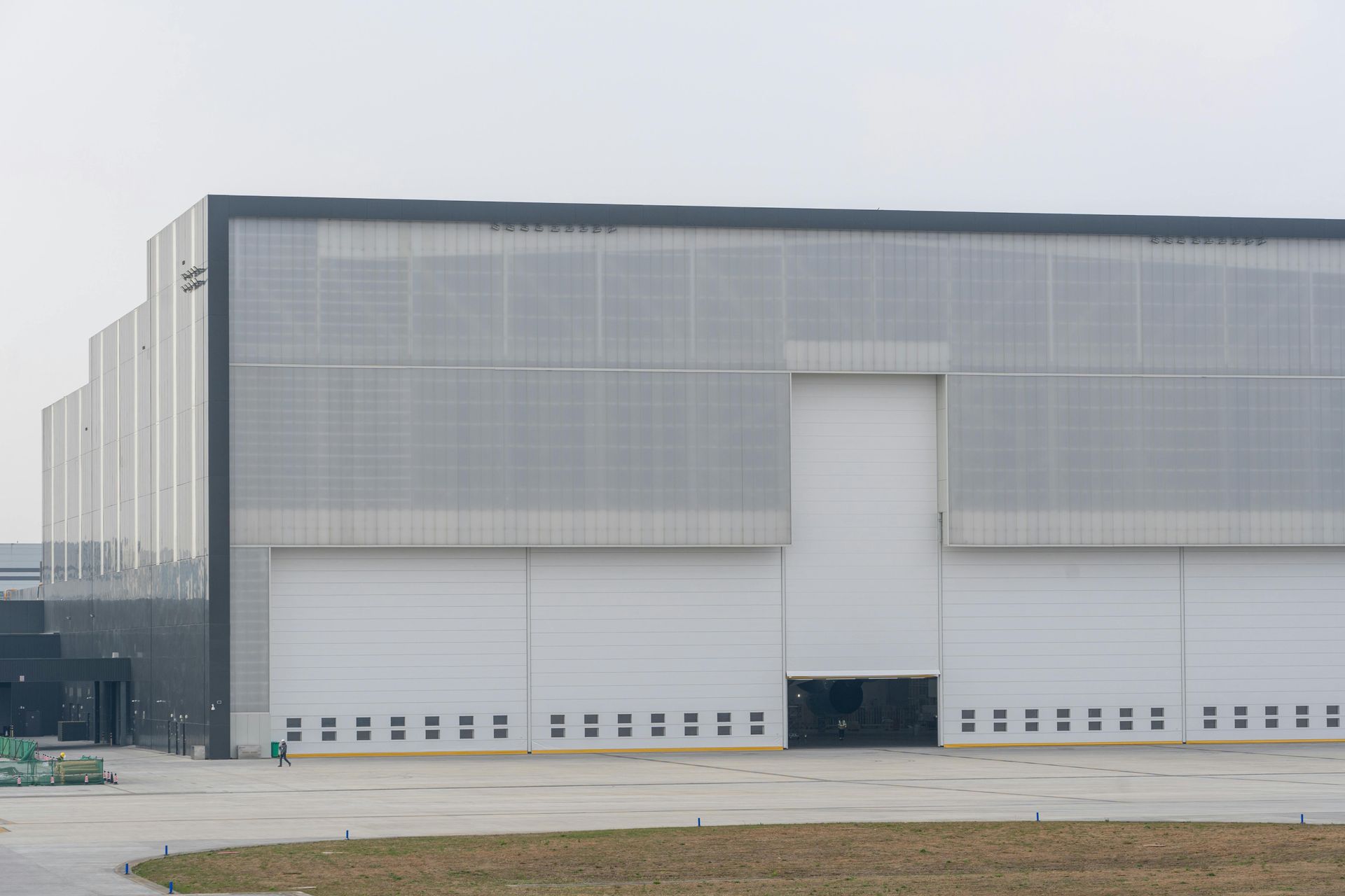 Large white industrial warehouse with a loading dock and closed doors on an overcast day