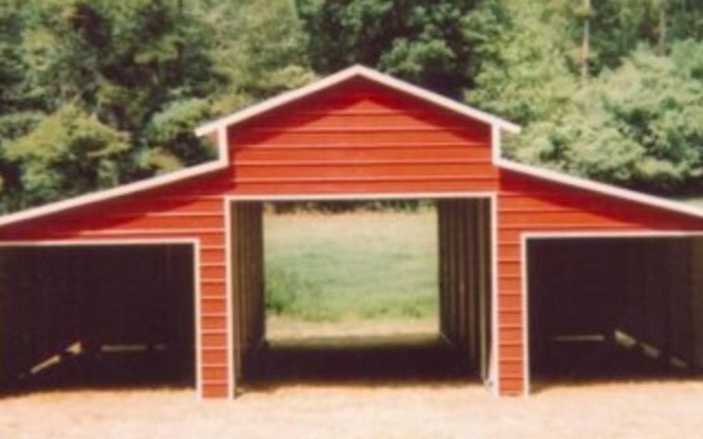 A red barn with white trim is sitting in the middle of a field.