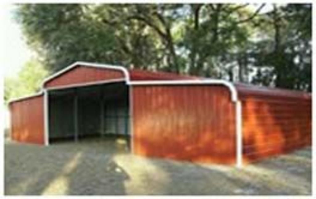 A red barn with a white trim is sitting on top of a dirt road.