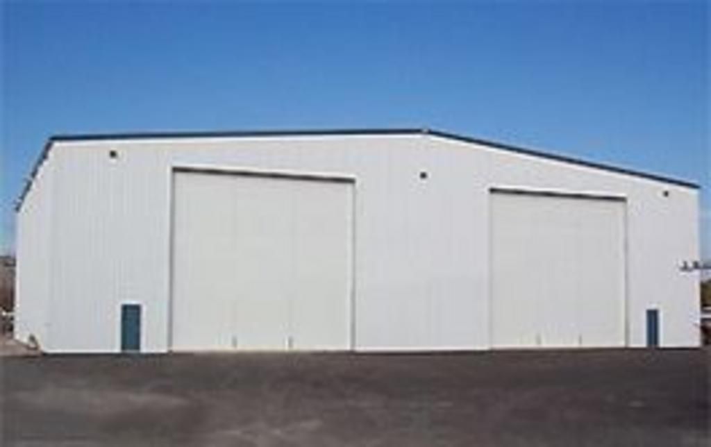 A large white building with a lot of doors and a blue sky in the background.