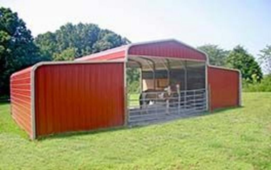 A red barn is sitting in the middle of a grassy field.