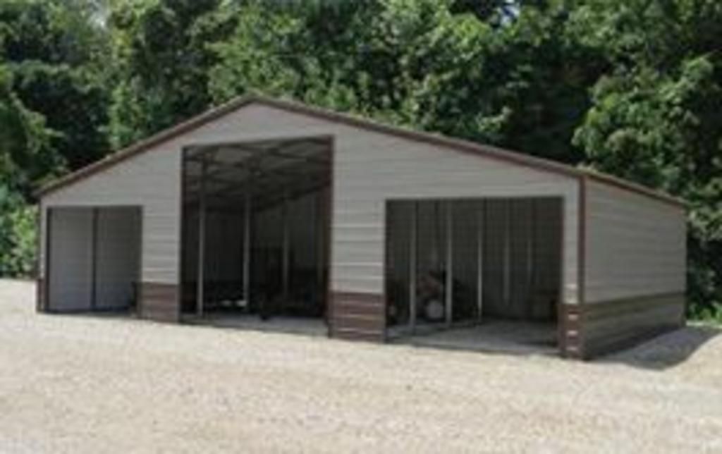 A large metal building with a lot of windows is sitting on top of a gravel road.