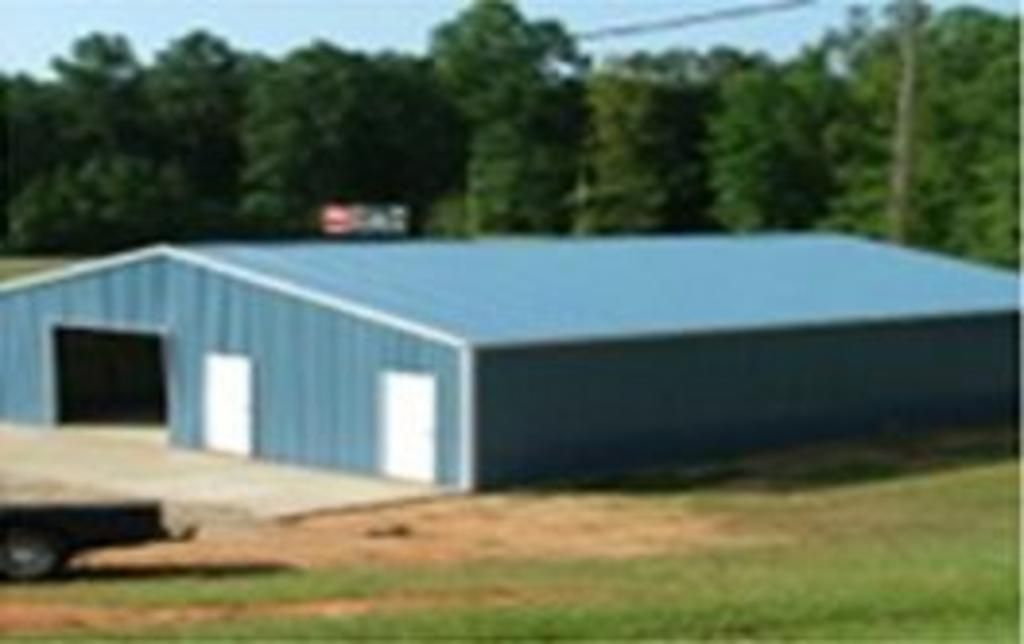 A truck is parked in front of a blue metal building.