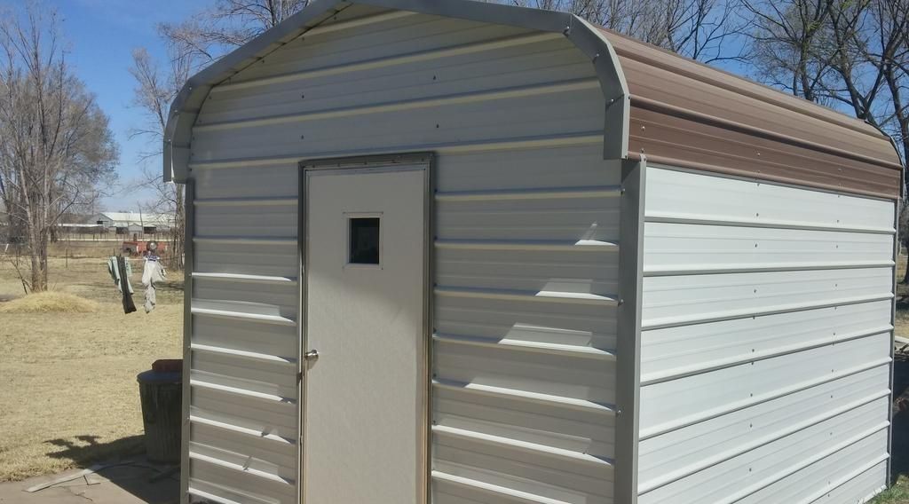 A small white metal shed with a brown roof