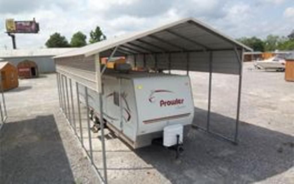 A trailer is parked under a canopy in a parking lot.