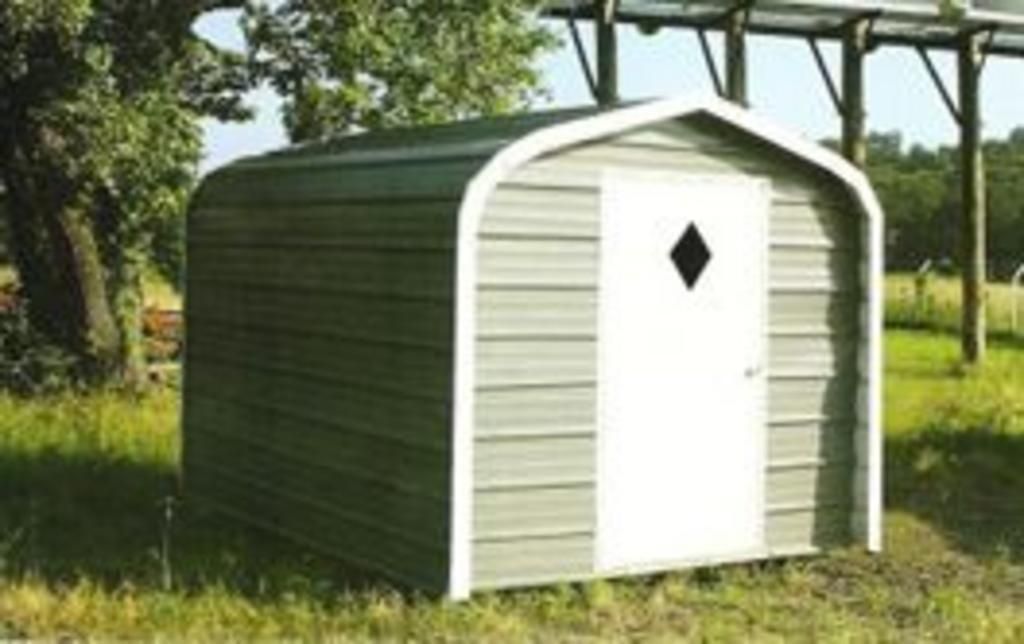 A small shed with a diamond shaped door is sitting in the grass.