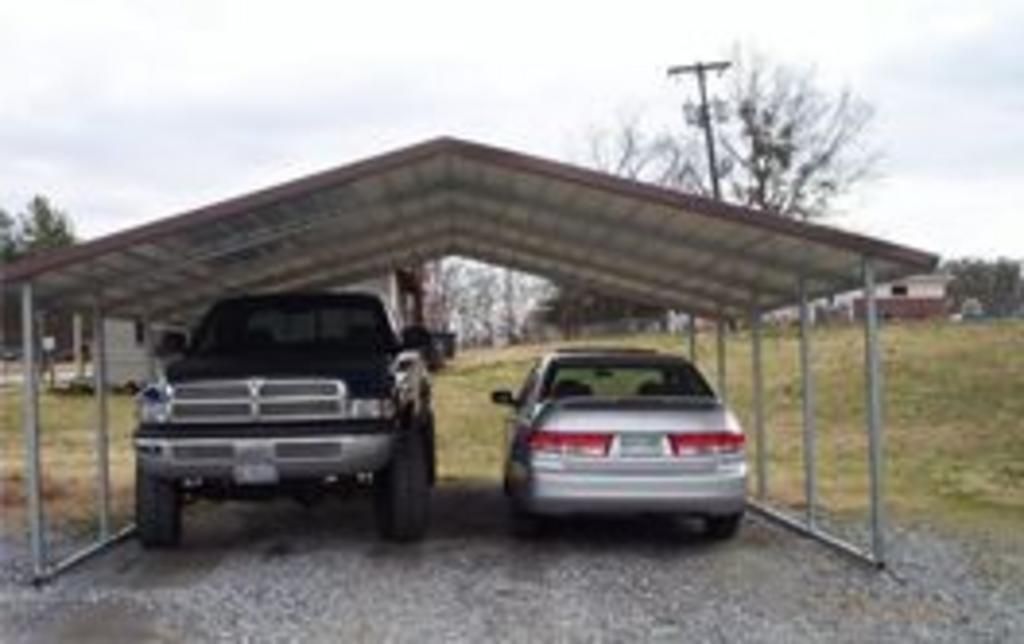 A truck and a car are parked under a carport.