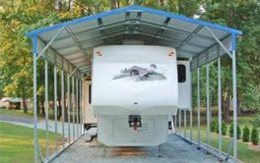 A white rv is parked under a blue carport.