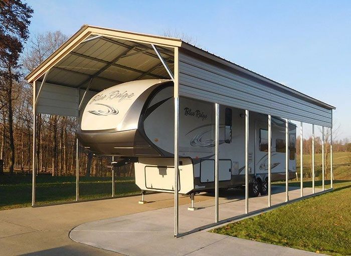 A white rv is parked under a carport.