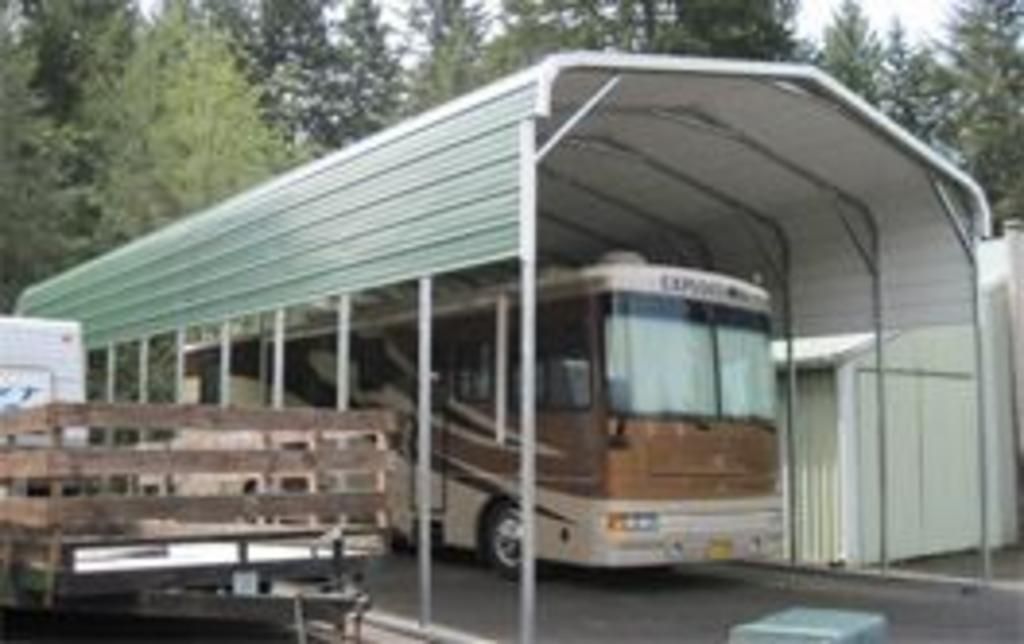 A rv is parked under a carport.