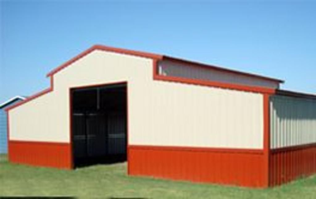 A red and white barn is sitting in the middle of a grassy field.