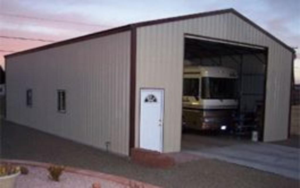 A rv is parked in a garage with the door open.