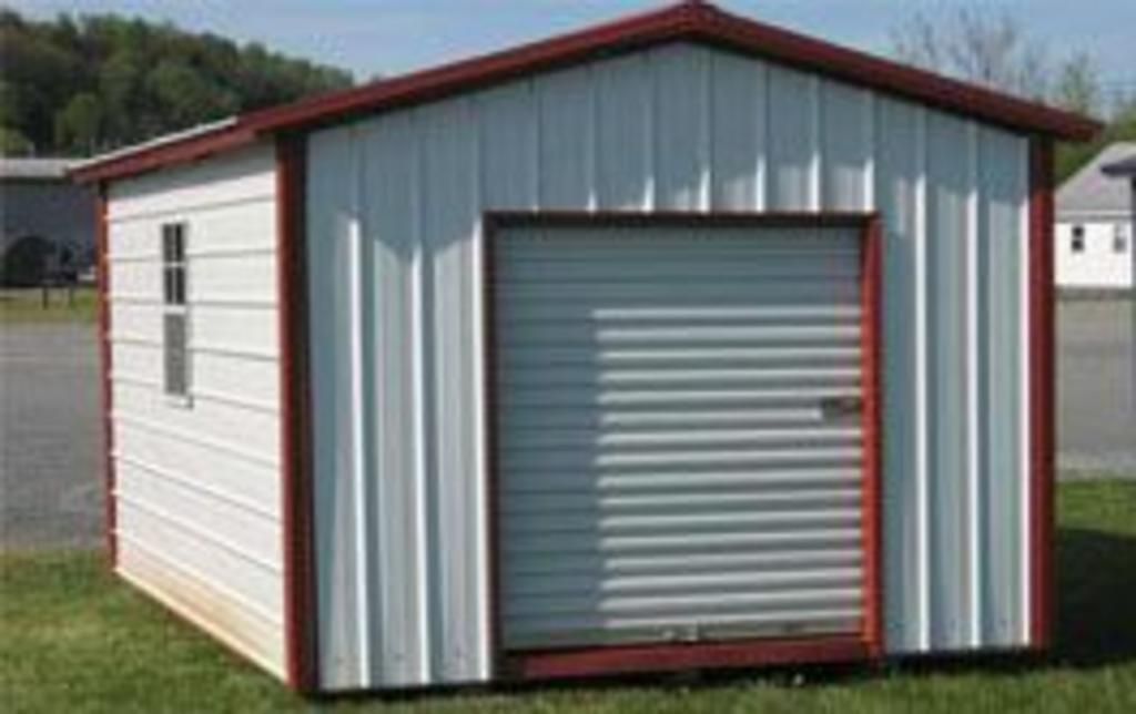 A small white shed with a red trim is sitting in the grass.